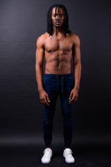 Fototapeta na wymiar Full body shot of young handsome muscular African man with dreadlocks shirtless