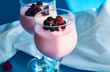 Dessert Panna cotta with currant berries in glasses on  leg is decorated with tea rose on blue...