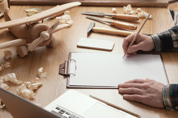 Craftsman designing a DIY project on a clipboard