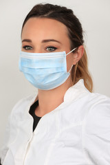 Jeune femme portant un masque chirurgical pour se proteger des virus sur fond blanc