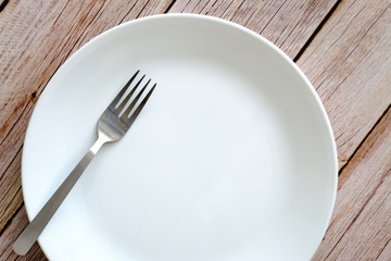metal Fork and white plate on the Table
