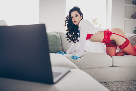 Photo of hot slim lady work home quarantine private online laptop chat undressing play hot lover naughty nurse role take off lab coat look screen cat position sofa wear red bikini tights indoors