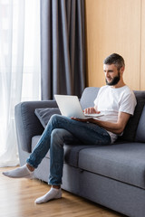 Freelancer using laptop while sitting on couch at home