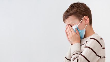 Side view of child with medical mask covering his face