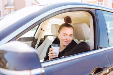 Fototapeta na wymiar Beautiful young lady sitting in car and drinking coffee take off