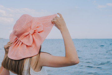 girl hold hat toward the sea 