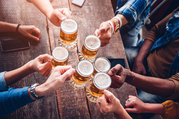 Gruppe von Menschen, die ein Bier in der Brauereikneipe genießen und anstoßen - Freundschaftskonzept mit jungen Leuten, die zusammen Spaß haben
