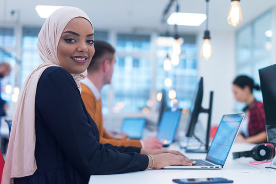 Young muslim African American business woman as a leader at work. Teamwork and multiethnic concept. Happy successful business leader working at her office, looking and smiling into camera.