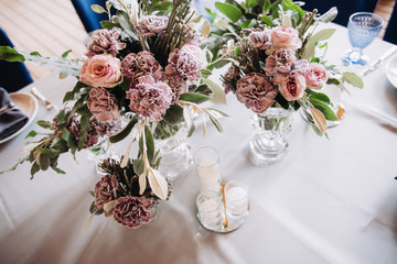 Wedding decor in purple and gray. Banquet tables with tablecloths are decorated with compositions of flowers, on the tables are plates, glasses and candles