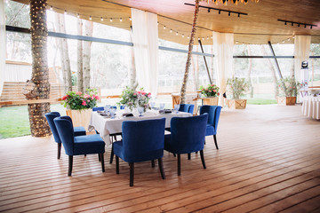 Banquet table is decorated with plates, cutlery, glasses, candles and flower arrangements