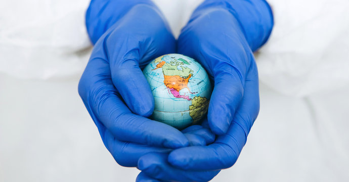 globe in the hands of the doctor. The inhabitants of the planet are fighting the coronavirus. The global pandemic COVID 19. globe in a medical mask.