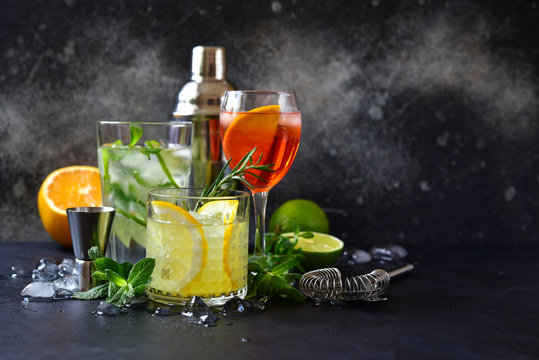 Three classic cocktails : aperol spritz, mojito and lemon cooler with rosemary with ingredients for making and cocktail set.