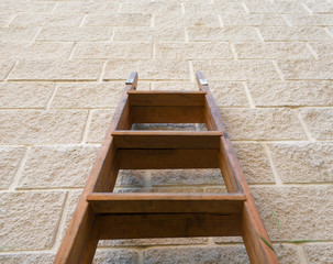 Old wooden ladder leaning against the wall, low angle view