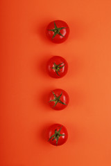  tomates rojos maduros sobre fondo naranja vistos desde arriba