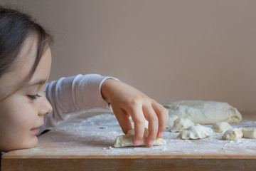 cute girl hands sculpts pies from the dough. homemade baking of bread, pizza, pasta on the background of a wooden table. Concept of cooking at home with children. Classes at home with parents