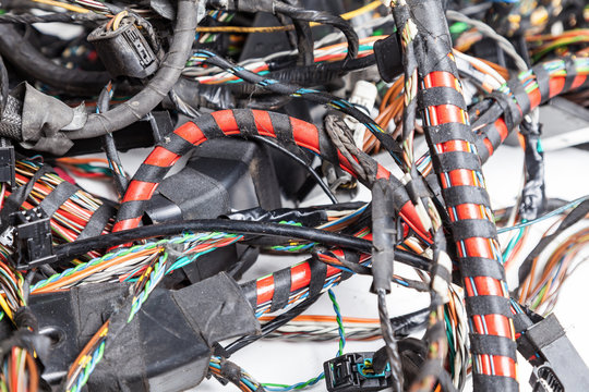 A red power channel rewound with black electrical tape close-up on a background of multi-colored wires twisted together. Tangled heap of digital channel wires.