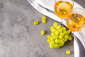 glasses of white wine, bunches of green grapes on a gray background, white towel top view