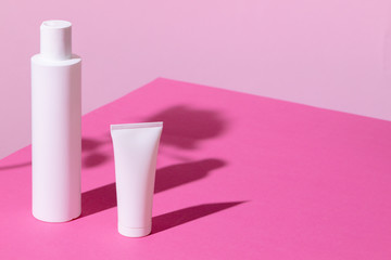 Skincare products containers on bright pink background close up