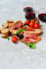 food flat lay italian  antipasti prosciutto, salami, bresaola olives tomatoes and grissini bread sticks. aperitif happy hour