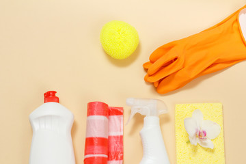 Rubber gloves, bottles of dishwashing liquid and sponges on a beige background.