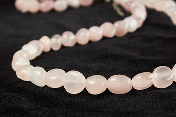 beads from rose quartz semiprecious stone on black velor. close up