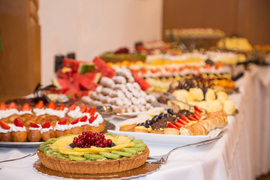 buffet with sweets. fruits and other sweets on dessert table. Rows of tasty looking desserts in beautiful arrangements. Sweets on banquet table - picture taken during catering event