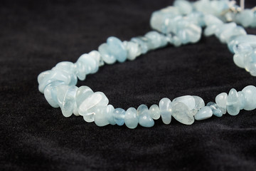 beads from aquamarine semiprecious stone on black velor. close up