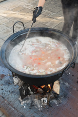 Cooking pot over campfire, stew preparing open grill steaming. Outdoor fireplace camping concept.