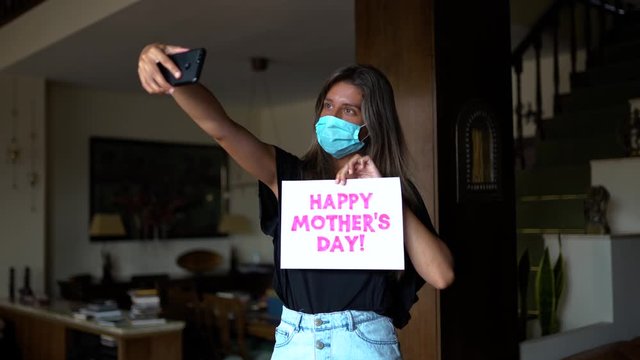 Chica con mascarilla haciéndose un video (modo selfie) para felicitar el día de la madre durante el confinamiento de COVID-19.