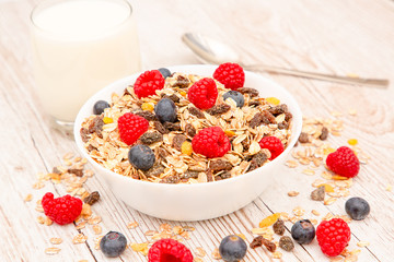 Breakfast Served in the morning with corn flakes Whole grains and raisins with milk in cups and Strawberry, Blueberry, Raspberry, Kiwi on the wood table,Diet food or healthy food in the morning.