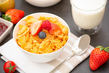 Breakfast Served in the morning with Coffee, Butter croissant and corn flakes Whole grains and raisins with milk in cups and Strawberry, Raspberry, Kiwi, Fresh Orange Juice on the breakfast table.