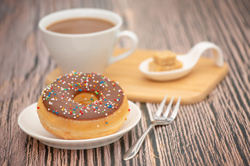 Dessert, Donuts, chocolate and strawberry circles, sugar and cream on Donuts and hot coffee cups, preparation for a break or party on the wooden table background.