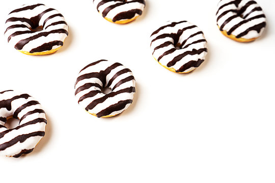 Glazed striped donuts on white background. Party food concept with copy space. Top view.