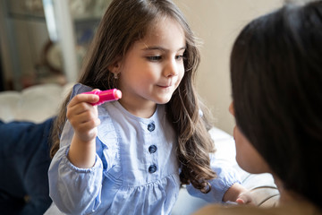 Happy loving family. Mother and daughter are doing make up and having fun at home. Close up portrait of daughter making up on her mom's face.