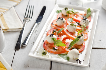 Caprese salad with tomatoes, mozzarella cheese and fresh basil leaves.