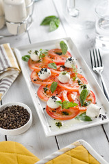 Caprese salad with tomatoes, mozzarella cheese and fresh basil leaves.