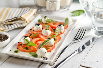 Caprese salad with tomatoes, mozzarella cheese and fresh basil leaves.