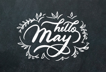 "Hello May" hand lettering inscription and hand drawn flowers on black chalkboard background.