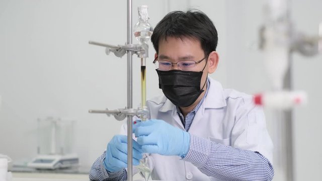 Scientists wear lab coat and mask and do separation samples by using column chromatography techniques. Silica gel was packed into a glass column and used solvent to elute sample out in the laboratory