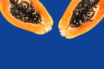Ripe juicy papaya cut in half with bright orange dent on classic dark blue background. Tropical nature fruits summer vacation fun healthy lifestyle concept