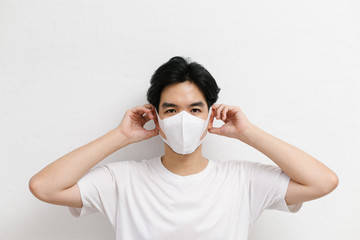 Young asian male wearing medical face mask to protect corona virus, studio portrait.