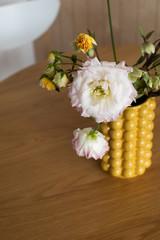 Bouquet in a yellow ceramic designer vase. It's on the table .