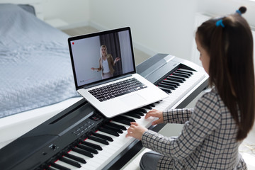 Fototapeta na wymiar Little girl distance learning the piano online during quarantine. Coronavirus concept.