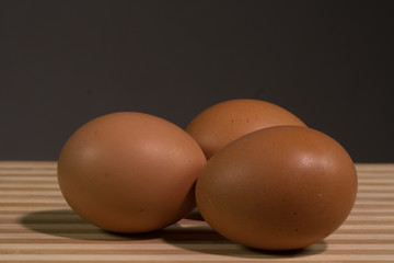 Three brown chicken eggs black background, close up.