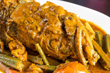 Close-up on serving of popular curry fish head with okra and tomato