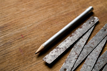 Measuring iron folding meter old, photographed on a shabby wooden surface.