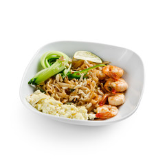 Fried udon noodles in a wok with shrimp and nuts. Served with fresh cucumber and lime. Traditional asian food. Isolated on a white background.