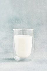 Glass of milk on blue background. Recipe of Korean drink latte with foam of instant coffee. DIY, instruction.
