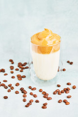 Trendy homemade Dalgona coffee in glass on blue background. Recipe of popular Korean drink latte with foam of instant coffee. DIY, instruction.