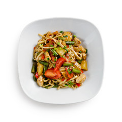 Fried udon noodles in a wok with chicken, string beans and pineapple slices. Traditional asian food. Isolated on a white background.